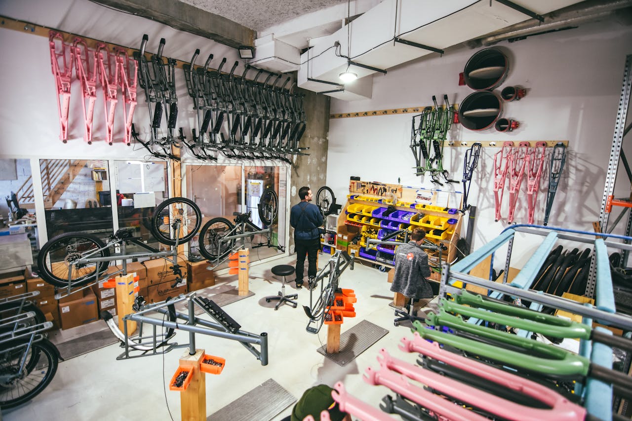Busy bicycle workshop in Bordeaux, featuring colorful frames and various tools, with two adults working.