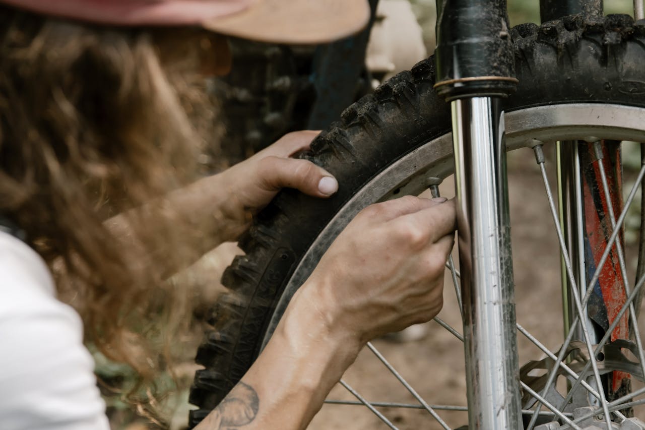 Close-up of mechanics hands fixing a dirt bike tire in an outdoor setting.